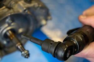 Mechanic using pneumatic wrench to tighten bolts on engine part photo