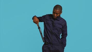 Portrait of security agent removing baton from belt, using it to secure assigned post, studio background. African american guardian pointing finger to truncheon, handling security breaches, camera B photo