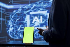 Developer analyzing complex AI brain models on green screen tablet. IT specialist using machine learning software on chroma key device to develop artificial intelligence technology photo