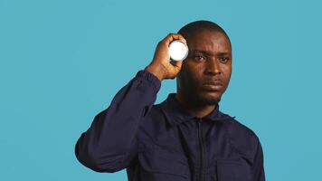 Headshot portrait of security employee tasked with evicting trespassers, turning on flashlight. Close up shot of patrolling agent using lantern, spotting intruders, studio background, camera B photo