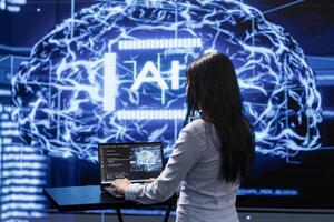 Programmer analyzing complex AI brain models on laptop, running simulations. Female employee using machine learning software on notebook device to develop artificial intelligence technology photo