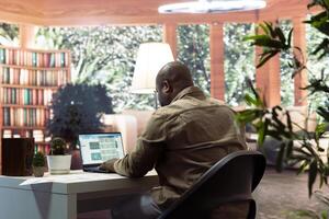 Sales manager examines financial reports and performance metrics to assess the expansion plans from his home office. Business consultant reviews online infographics, balance and expenses. photo
