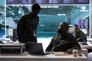 Experts collecting real time cctv data and transmitting crucial information to help troops in the field. Soldiers collecting important details from classified files in command post power base. photo