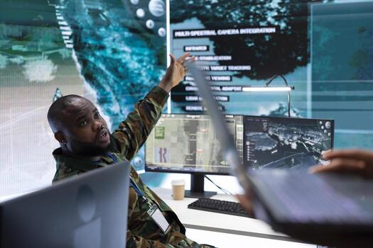 Army expert in a modern base of operations with satellite data, handling surveillance operations with real time information. Coordinating security measures and protecting national interests. photo