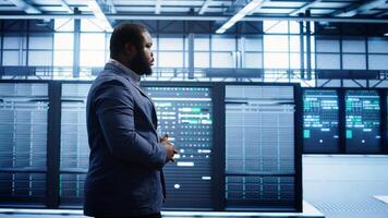 Admin inspecting server farm equipment, walking between supercomputers. IT specialist doing evaluation of data center workspace, checking equipment, monitoring performance, camera B photo