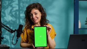 Jolly woman filming tech tutorial on how to repair damaged mockup tablet. Joyous tech professional in home studio teaching subscribers to install operating system on isolated screen device, camera A photo