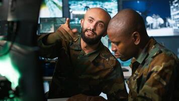 Army unit working in governmental facility next to coworker, doing brainstorming, operating surveillance tech. Team of soldiers doing job in HQ base of operations, camera A photo