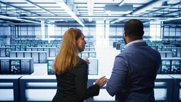Teamworking admin colleagues inspecting server room hardware. IT expert and colleague supervising data center establishment, checking equipment, monitoring performance, camera B photo