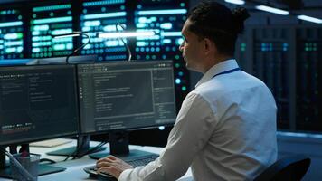 Engineer overseeing data center, making improvements and updates to ensure system can handle networking tasks, handheld camera shot. Indian man in server room tracking network traffic, camera A photo