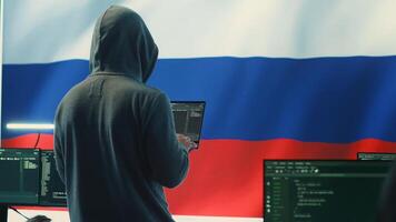 Propagandist person in a Russian cybersecurity center with the national flag works on installing fear and anxiety among the population by manipulation and brainwashing, cyber conflicts. Camera A. photo
