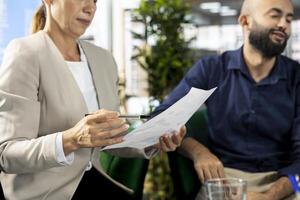 Staff member in modern diverse startup office showing manager progress on customer commissioned project. Accountant presenting team leader key data statistics after business audit photo