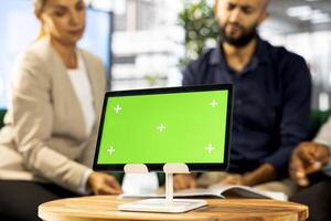 Arab colleague using isolated screen device, doing briefing meeting to share new ideas for profit growth. Team of employees in office talking with director, using mockup tablet, close up photo