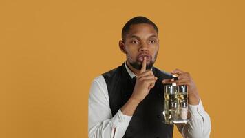 Catering staff waiter doing a mute sign for silence and privacy, keeping quiet while he carries cruet set with condiments for customer satisfaction. Shows a hush symbol to keep secret. Camera A. photo