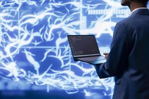 System administrator working on laptop, programming artificial intelligence computing simulating human brain. Man in workspace using notebook, building AI machine learning algorithms photo