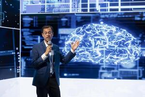 Company manager presenting how AI technologies can bring increased productivity in business sector during conference. Businessman using mic to discuss about about implementation of AI driven solutions photo