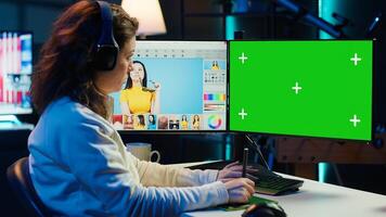 Photographer wearing headphones using advanced photo editing software on green screen monitor to upgrade images. Photo editor utilizing photographs retouching application on mockup PC, camera A