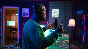 Young artist singing his new song creation on microphone gear, editing his recordings to adjust volume levels with mix and master techniques. Singer composing a melody, stereo tools. Camera B. photo