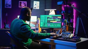 Artist playing piano electronic keyboard and recording new sounds, producing new midi controller notes in his home studio. Audio producer working with digital audio workstation software. Camera B. photo