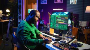 Talented artist composing new lyrics for his tracks and recording music with audio devices in his home studio. Singer composer writes melodic material by taking notes and creating rhymes or songs. Camera B. photo