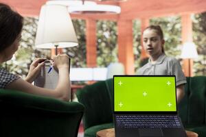 Adolescent in therapy session focused on mental health next to isolated mockup screen, works on emotional well being. Psychotherapist supporting the teen to manage anxiety and depression. photo