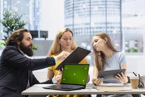 Clients looking over personalized planning guide on green screen laptop written by financial advisor during meeting. Consultant optimizing living expenses for customers using mockup notebook photo
