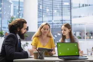 Financial advisor using isolated screen laptop to provide stock recommendations to individuals. Agent in office helping his clients make sound investment decisions using mockup notebook photo