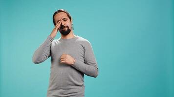 Man feeling exhausted from overworking and lack of sleep, rubbing eyes and yawning, isolated over studio background. Tired person feeling sleepy, being fatigued, studio backdrop, camera B photo