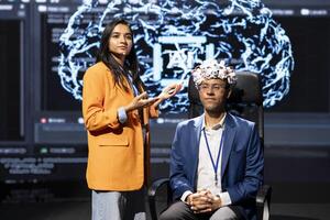 Speaker does EEG headset presentation during tech convention, demonstrating successful implementation of AI in driving forward startup businesses, sharing latest neuroscience discoveries photo