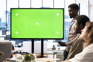 Team members from a business corporation use isolated mockup screen, discussing details and progress for a new project during corporate meeting. Employees informed about marketing developments. photo