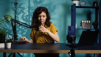 Content creator doing relaxing ASMR type of for fans, filming in her apartment. Online show host using professional microphone to whisper and put viewers to sleep, camera B photo