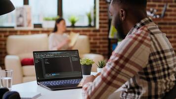 Male programmer developing an app on his laptop and working remotely. Home office setup includes digital tools and focuses on software engineering and coding, IT specialist. Camera B. photo