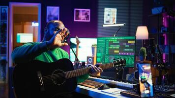 Talented performer teaching how to play acoustic guitar online for a tutorial, hosting internet master class to provide advice for beginners. Artist composer explaining accords on strings. Camera B. photo