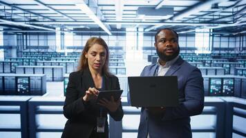 Manager in data center supervising worker running error checking utilities to fix errors. Supervisor in server farm overseeing engineer repairing network issues affecting rigs performance, camera B photo