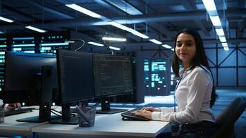 Portrait of smiling engineer overseeing data center, making improvements and updates to ensure system can handle networking tasks. Upbeat server room worker tracking network traffic, camera B photo