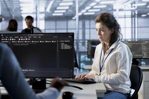 Programmer at work implementing cybersecurity measures to protect data center. Server hub facility IT specialist monitoring and analyzing metrics with device to enhance operational effectiveness photo