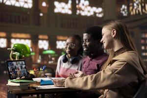Diverse group of pupils attending online class webinar from the campus library, participate at remote courses while they can work on their bachelor degree. Academic research within the institute. photo