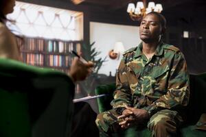 Female psychologist assists a black soldier in a counseling session, focusing on PTSD and trauma after combat distress. Mental health support for army veterans, grief and guilt. photo
