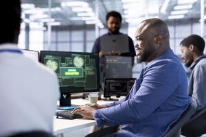 Cheerful engineer in data center getting access granted notification on PC screen, managing to access server files after they were locked by hacker using ransomware, receiving help from colleagues photo