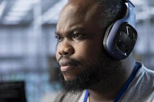 Close up of data center expert listening music and writing disaster recovery plans ensuring minimal downtime. Server farm technician wearing headphones uses analytics to monitor performance photo