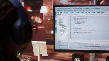Engineer in home office looking at UI on computer monitor, typing and executing programming code. Close up of person using coding application to write and test code in modern apartment, camera A photo