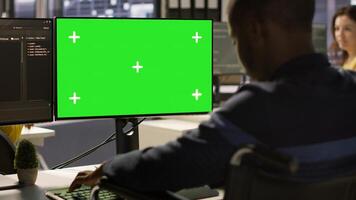 Man with disability in inclusive workplace working with machine learning tech on green screen computer. African american IT expert with paraplegia in wheelchair works with data on mockup PC, camera A photo