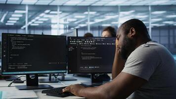 Overworked engineer falling asleep while typing on computer in server hub, monitoring data center energy consumption. Tired technician struggling to stay awake while inspecting rackmounts, camera B photo