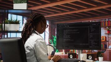 Programmer types code into PC, entering commands, running script. African american IT professional in apartment fixing errors in application, implementing new features, camera A photo