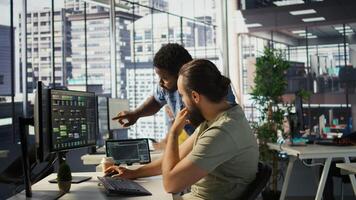 Manager correcting programmer mistakes while conducting code review to fix errors, identifying technical issues with company software. Team leader supervising IT staff member optimizing code, camera B photo