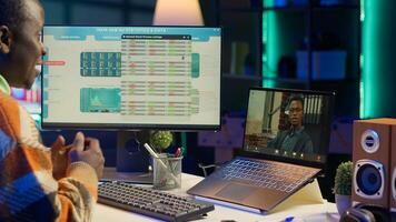 Black man waving on call and discussing about business infographics, reviewing monthly budget balance and working remotely. Staff focused on conversation during online meeting on pc. Camera A. photo