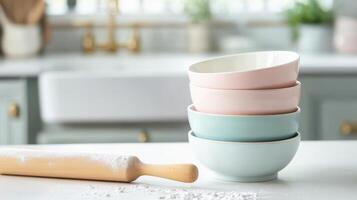 Stack of pastel ceramic bowls with wooden rolling pin in bright kitchen setting photo