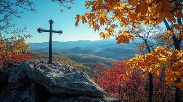 Autumn landscape with cross on rocky hill overlooking mountain range and vibrant foliage photo