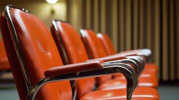 Row of red theater chairs with chrome armrests in auditorium setting photo