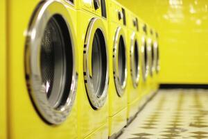 Bright Yellow Laundromat Interior with Modern Washing Machines in a Row photo