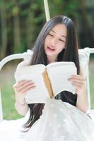 Young Woman Reading Book in Nature with Soft Light and Greenery photo